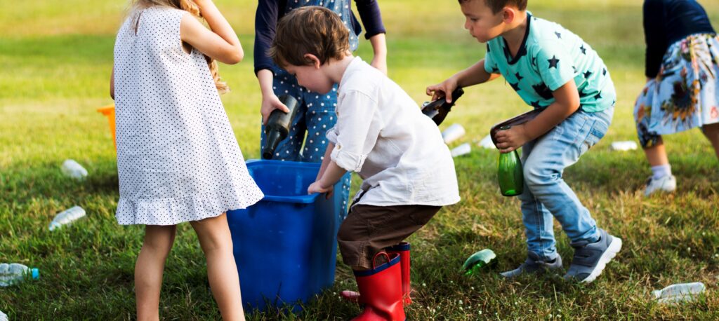 Barn samlar flaskor och andra saker i en låda. 